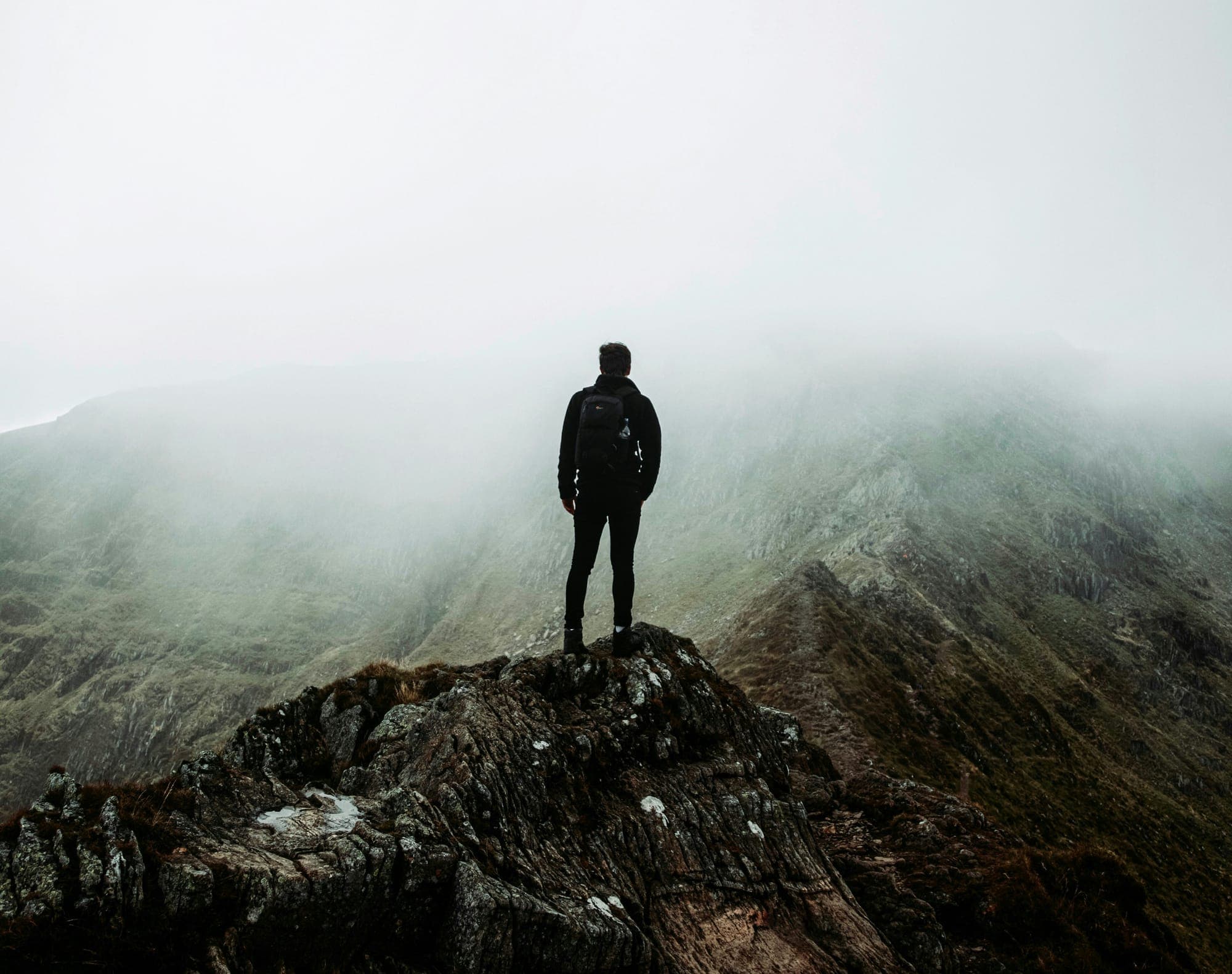 A man standing on a mountain ridge in fog